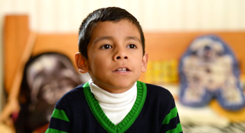 Niño con suéter azul marino y franjas verdes
