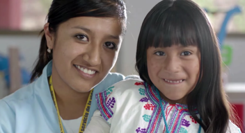 Terapeuta y niña sonriendo a la cámara