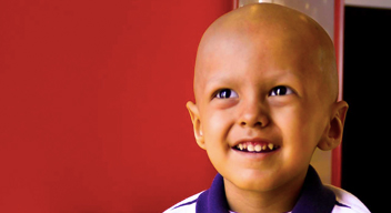 Niño sin cabello sonríe mirando al cielo en los pasillos del HITO