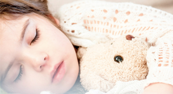Niña dormida abraza a un oso de peluche