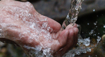 Fotografía de una mano atrapando un chorro de agua. Foto por Samad Deldar para Pexels