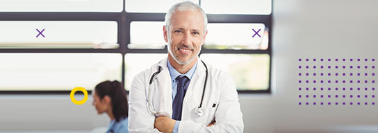 Profesional de la salud con los brazos cruzados sonríe a la cámara en consultorio
